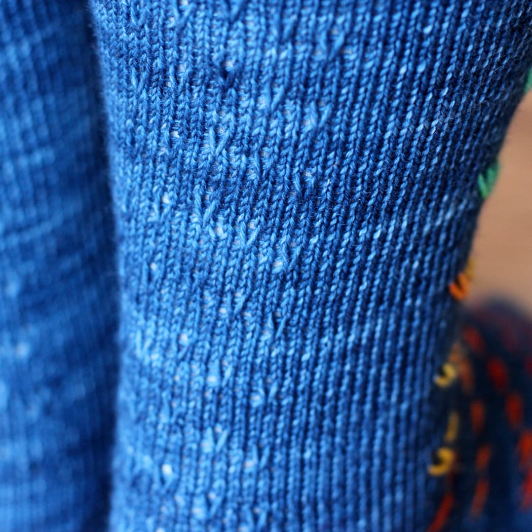Back view of blue socks with panel of subtle chevron slipped-stitch texture.