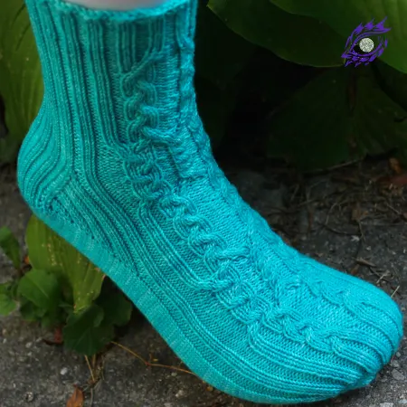 Foot wearing bright aqua knitted socks with intricate cable motif and ribbed accents.