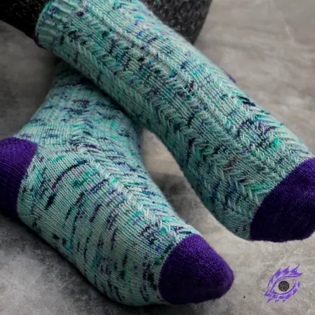 Feet wearing blue and purple knitted socks with columns of elongated-stitch cables.