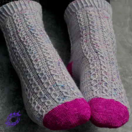 Feet wearing pink and light purple knitted socks with columns of mirrored elongated-stitch cables.