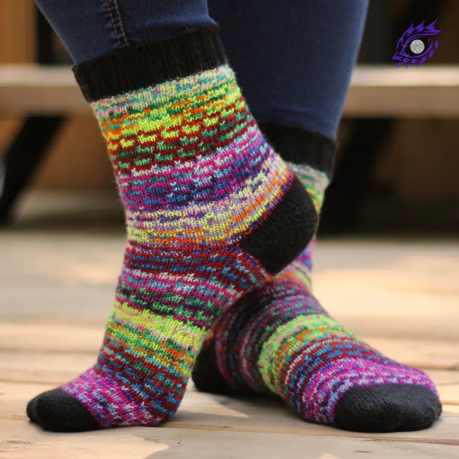 Feet wearing wildly-multicoloured socks with all-over spiralling stranded-colourwork motif.