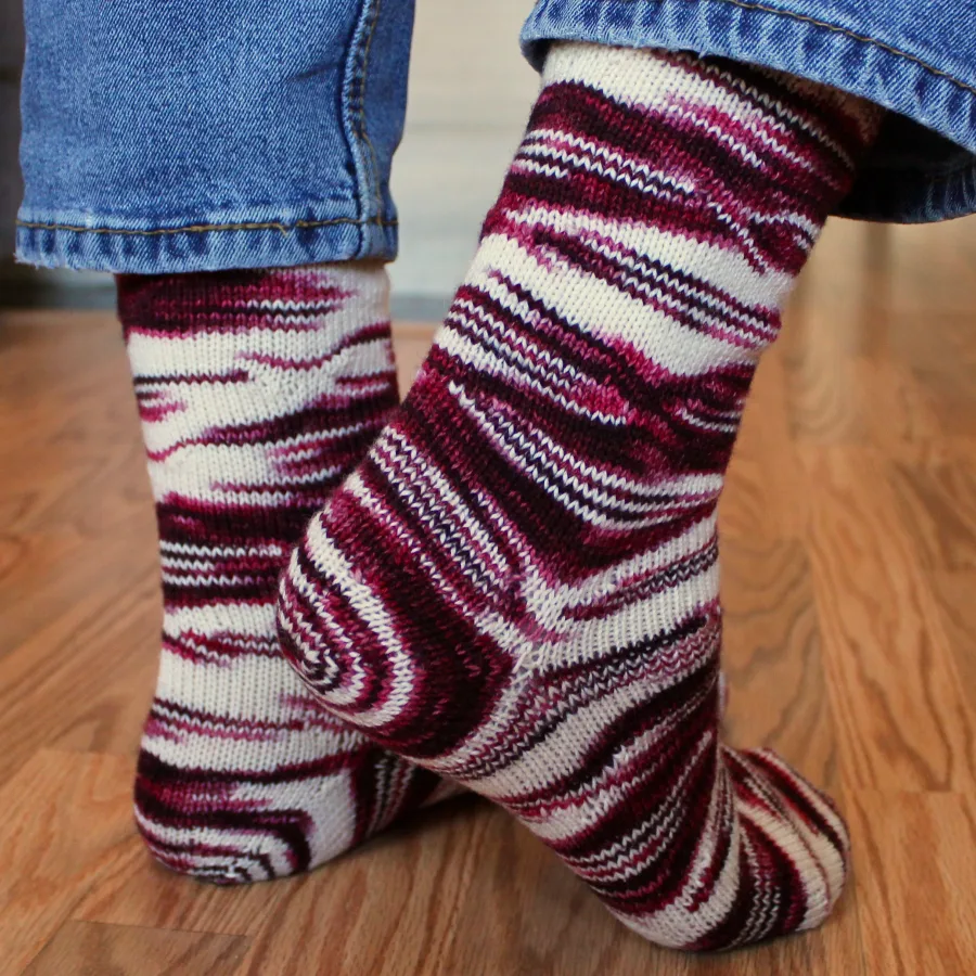 Side and back view of feet wearing red and white socks with distorted, oval-shaped pooling patterns.