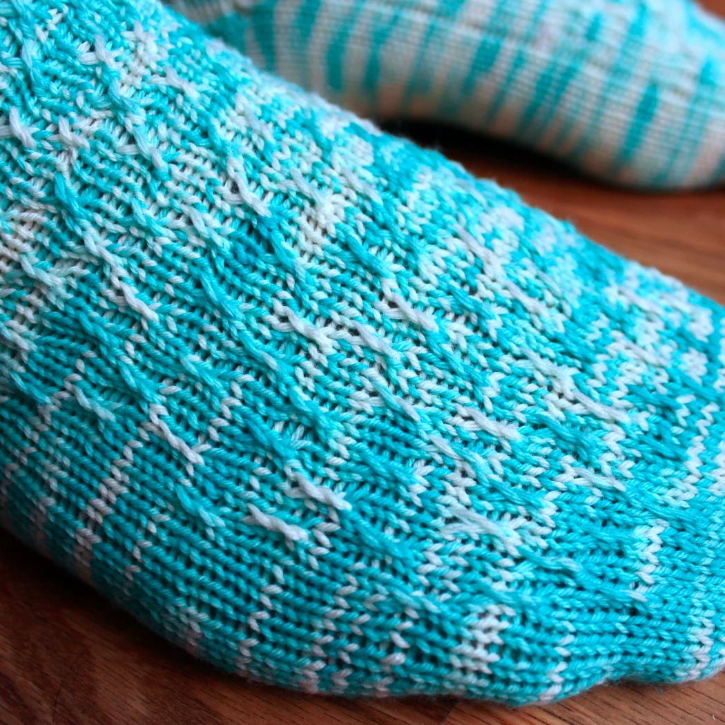 Close-up of bright blue and white sock with twisted surface detail.