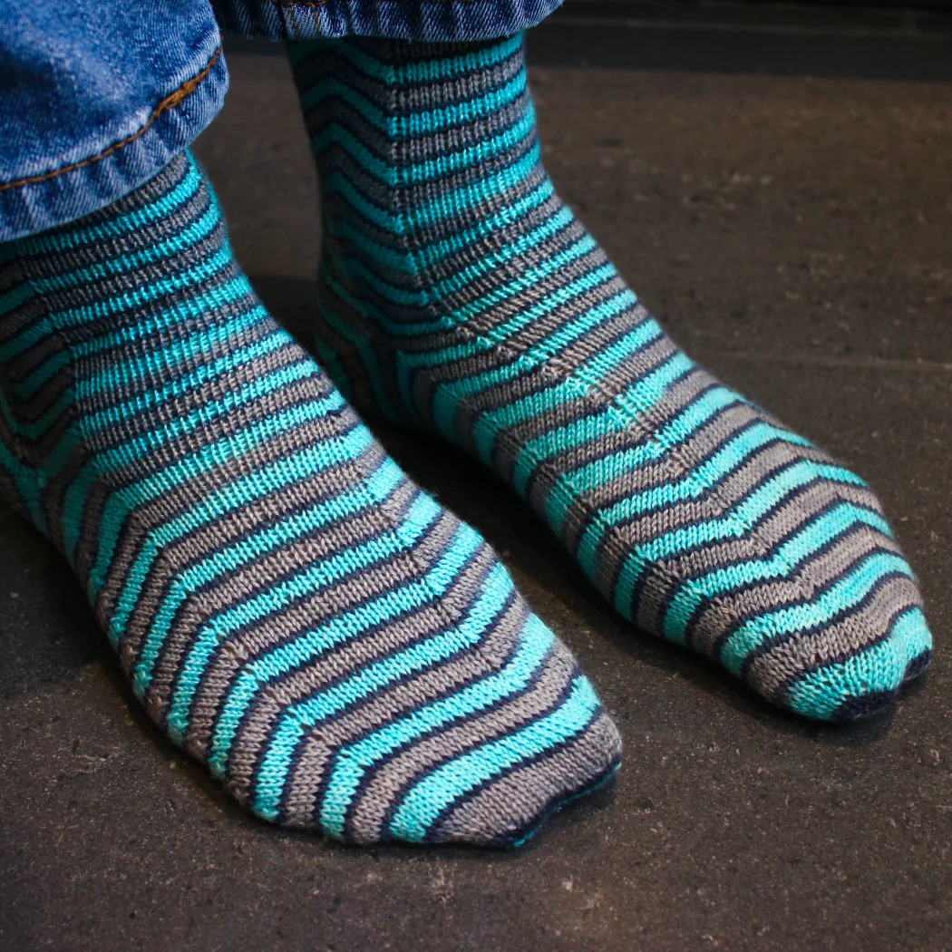 Front view of grey and blue socks with stripes that are distorted on the sides.