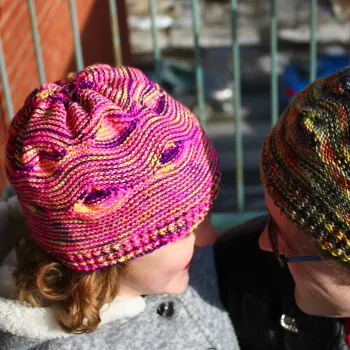 Child wearing yellow, pink, and purple hat with large wavy textured pattern.