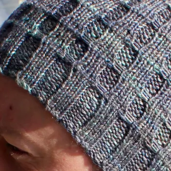 Close up of grey-blue hat with ribbing crossed by parallel lines.