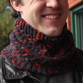 Man wearing cowl that is black with bright orange and burgundy highlights in a zigzag texture.