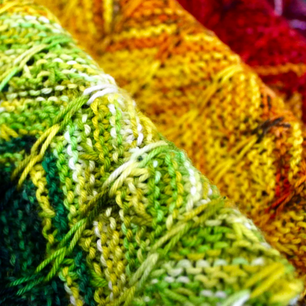 Close up of bright rainbow textured scarf bunched up in ripples.