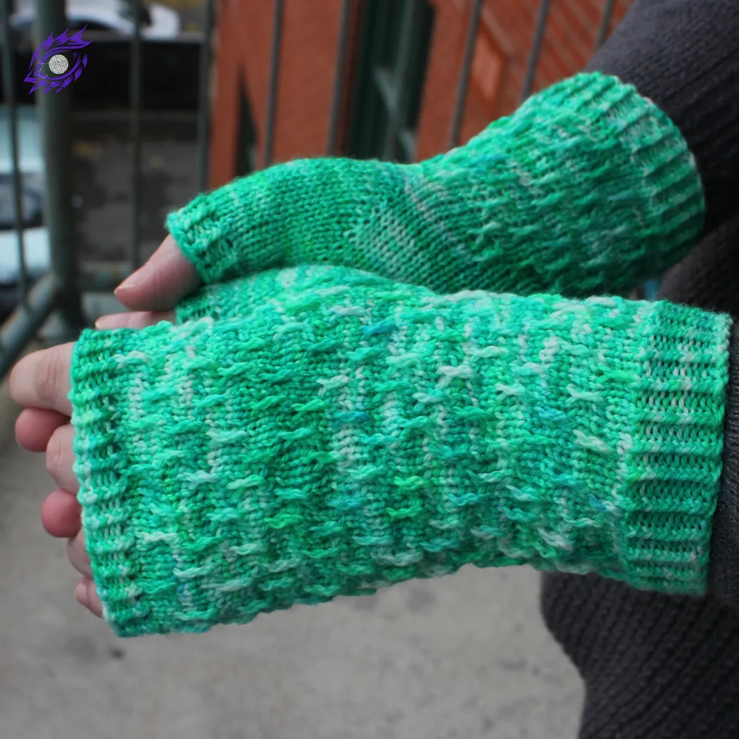 Side view of hands wearing bright green, white, and blue fingerless mitts with twisted surface detail.