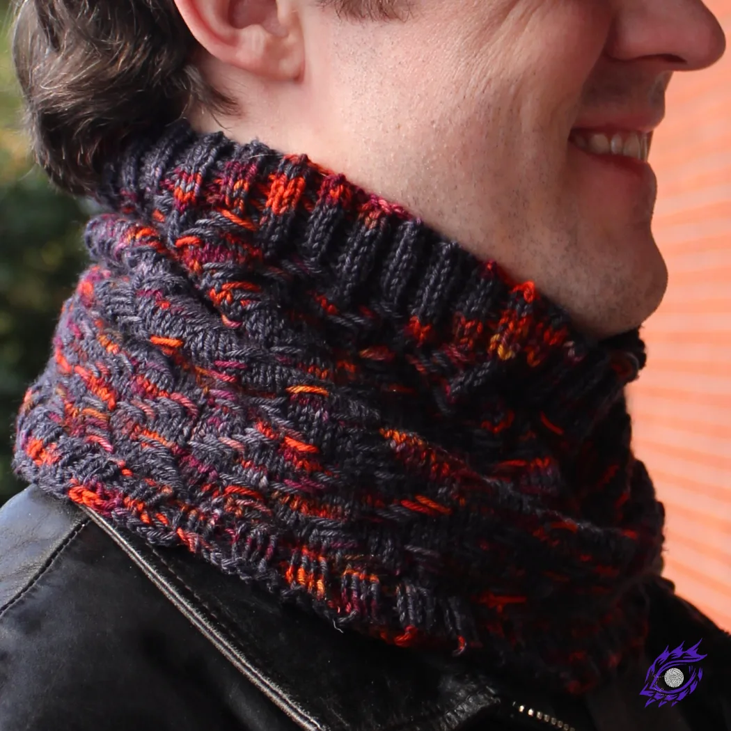 Man wearing cowl that is black with bright orange and burgundy highlights in a zigzag texture.