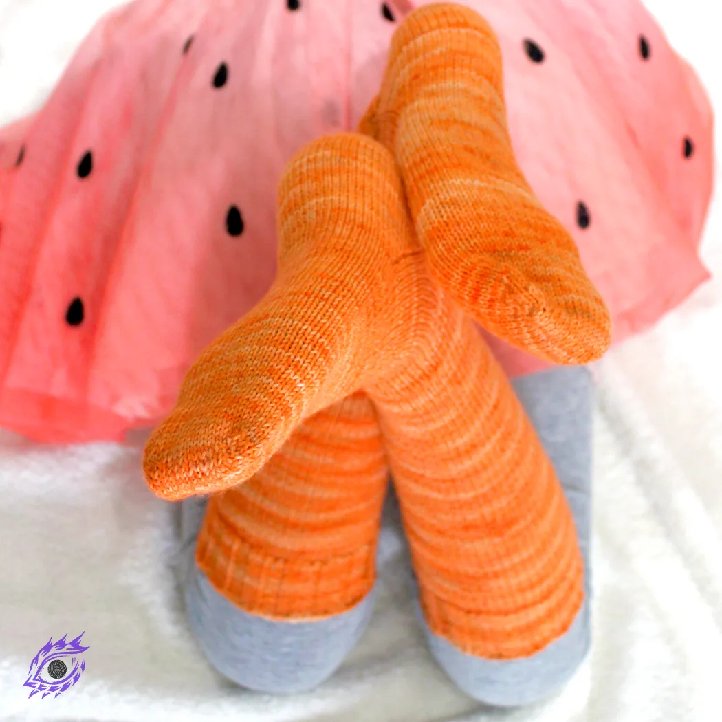 Crossed child feet wearing bright orange knee socks.