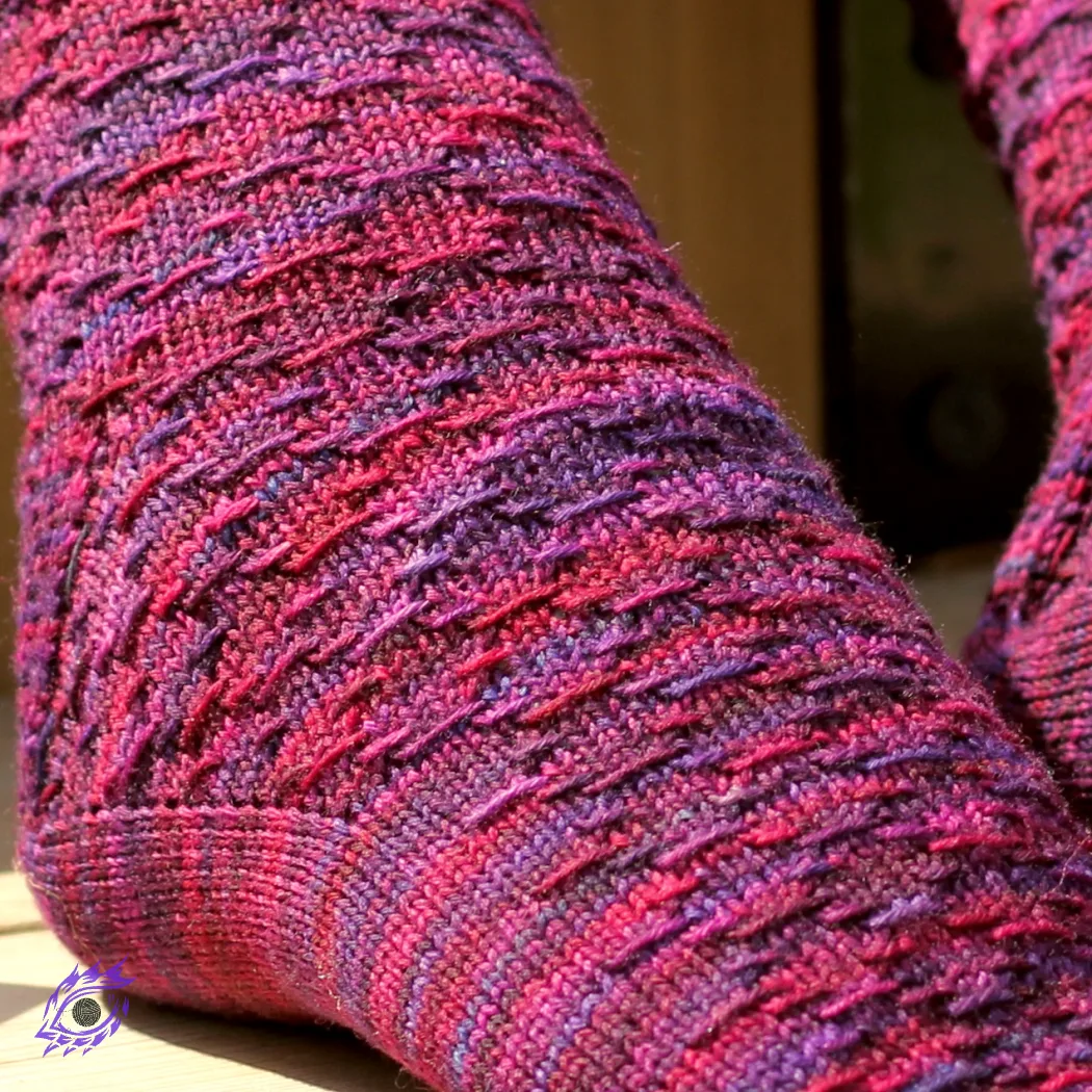 Close up of foot wearing red and purple sock with horizontal diamond-shaped surface texture.