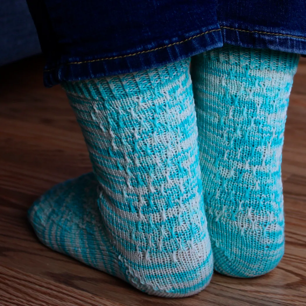 Back view of bright blue and white socks with twisted surface detail.