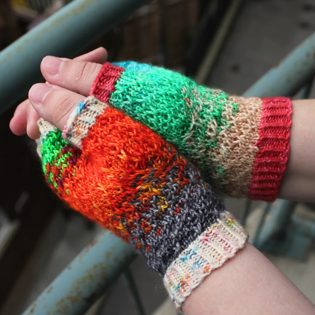 Side view of mismatched multicoloured fingerless mitts with slipped-stitch texture.