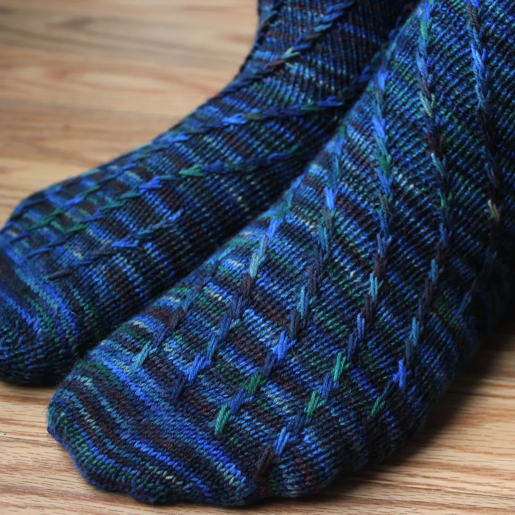 Close-up side view of dark blue socks with criss-crossing surface detail.