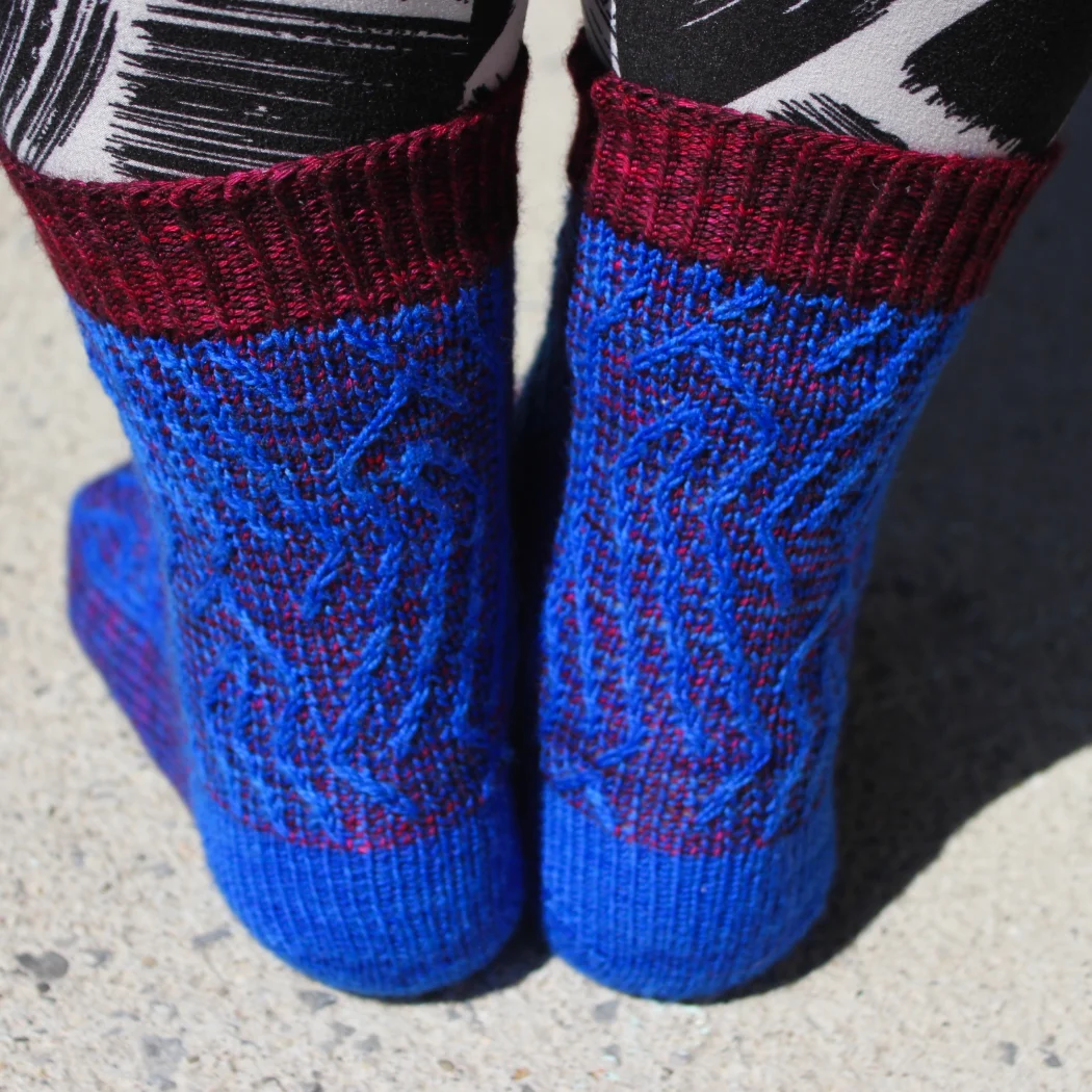 Back view of red and blue socks with vertical stripes that create an abstract surface texture.