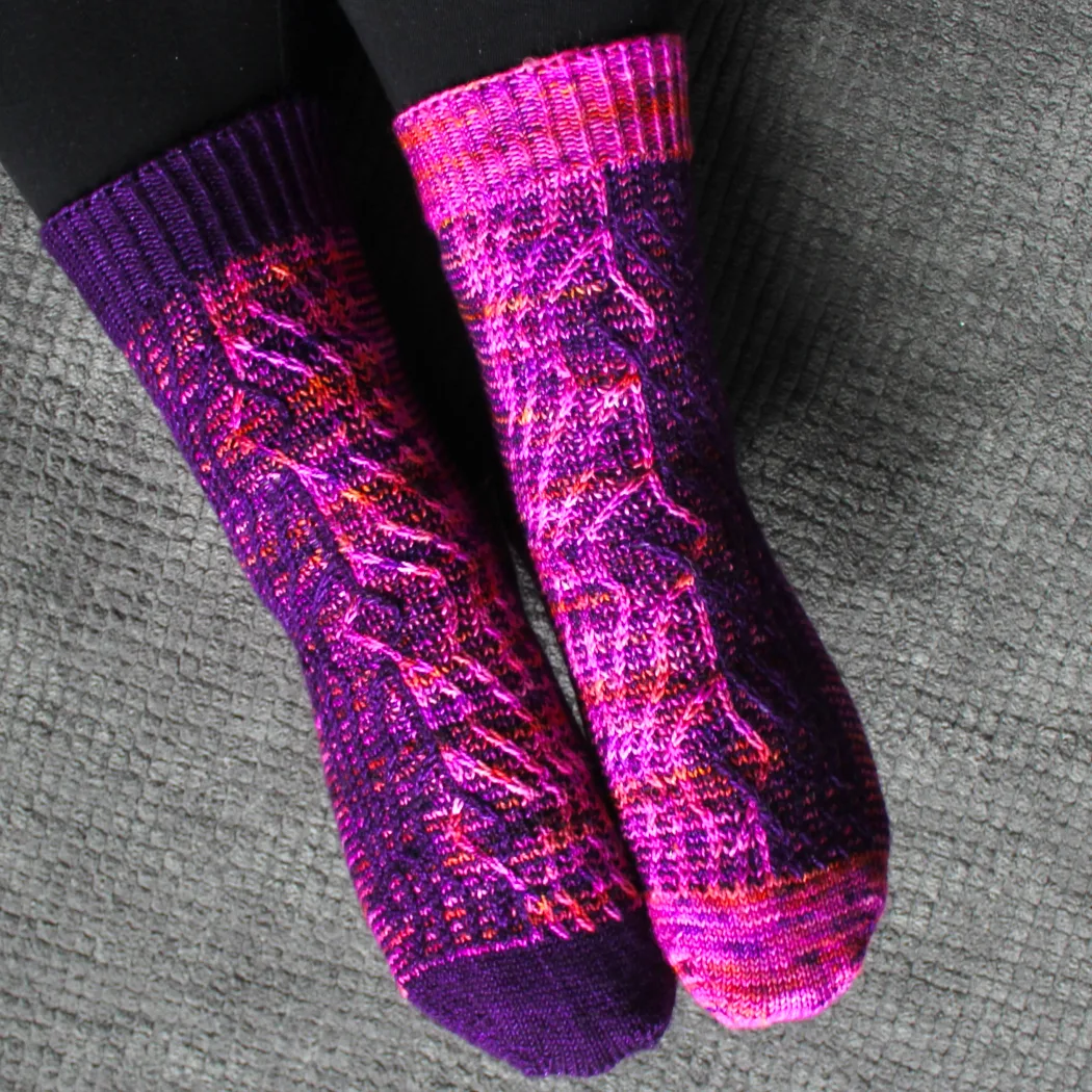 Top-down view of purple and pink socks with vertical stripes that create an abstract surface texture.