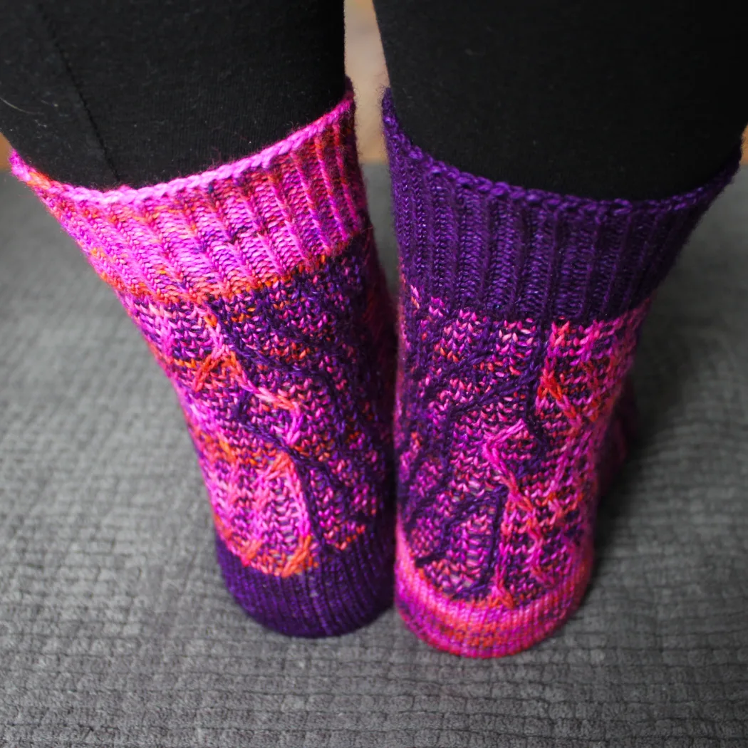 Back view of purple and pink socks with vertical stripes that create an abstract surface texture.