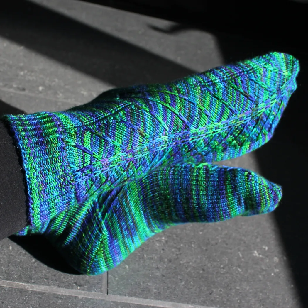 Crossed feet wearing blue-green socks with angled surface detail.