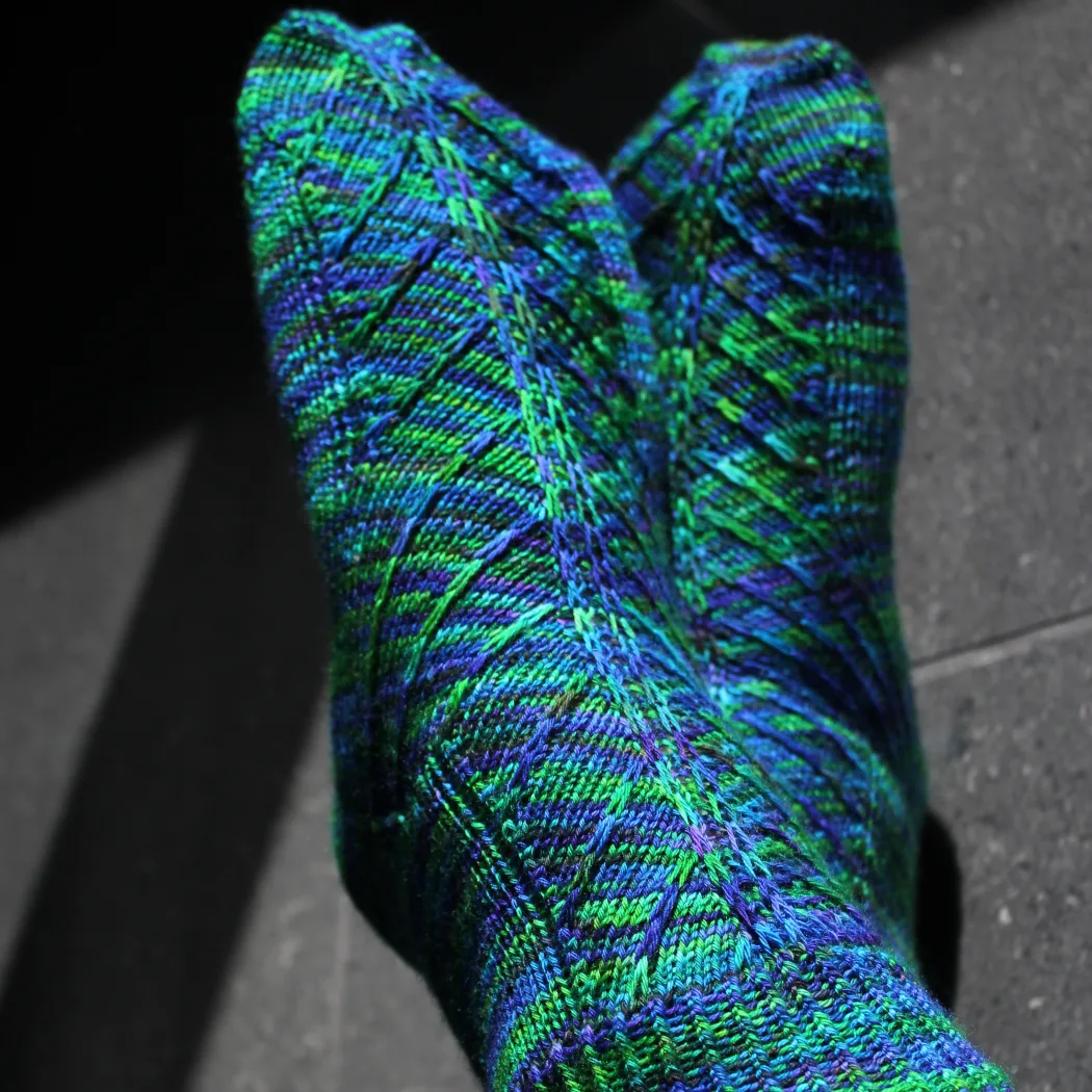 Crossed feet wearing blue-green socks with angled surface detail.