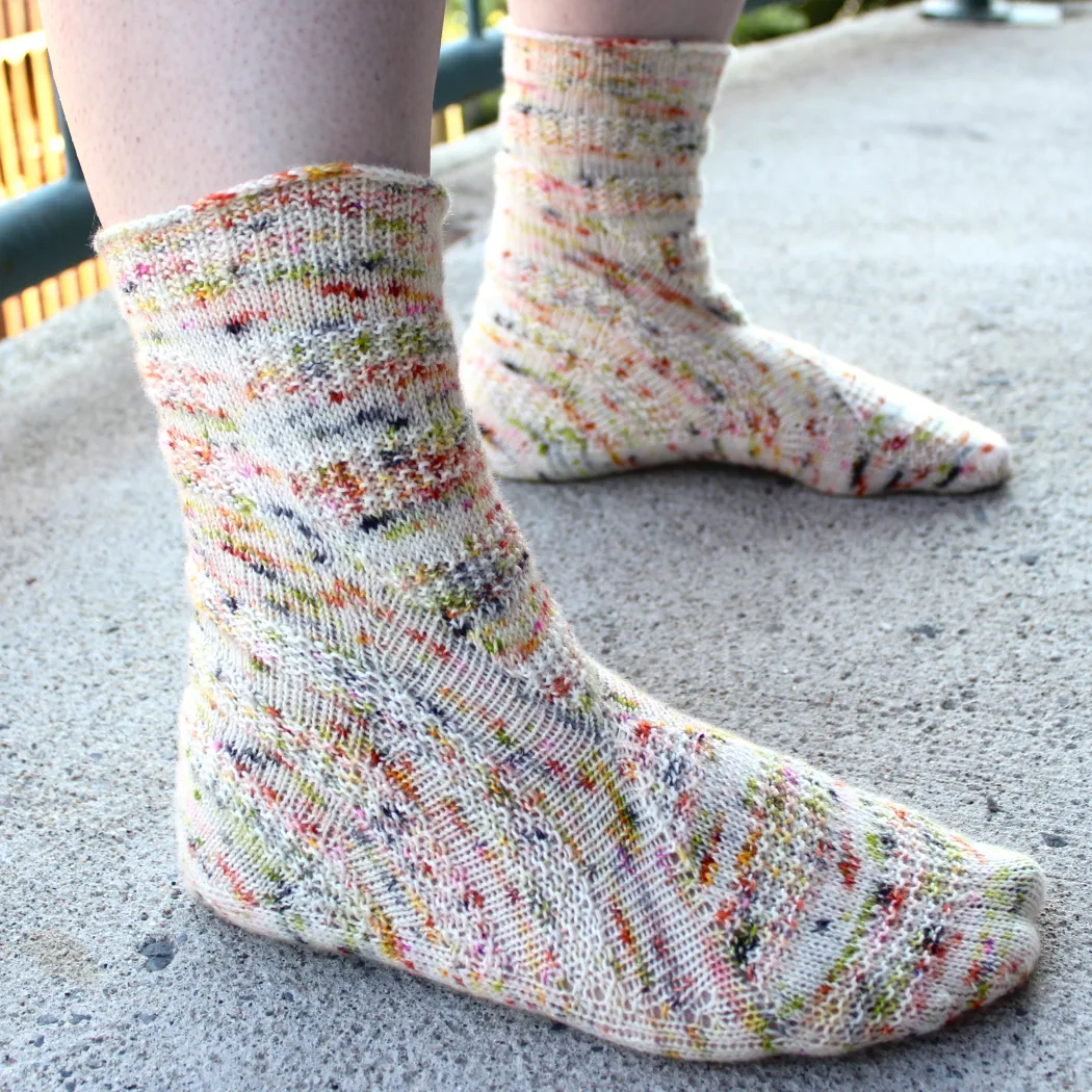 Side view of heavily-speckled white socks with semicircular texture details.