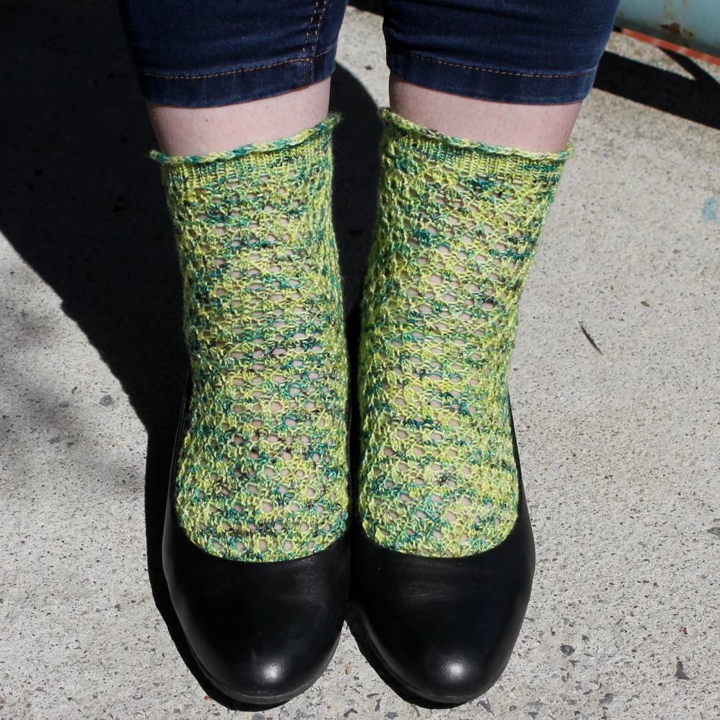 Front view of feet wearing black shoes and yellow and green lace socks.