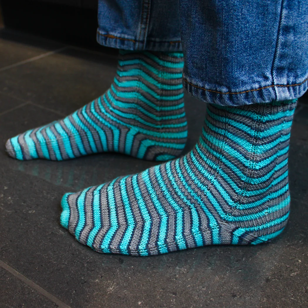 Left-side view of grey and blue socks with stripes that are distorted on the sides.