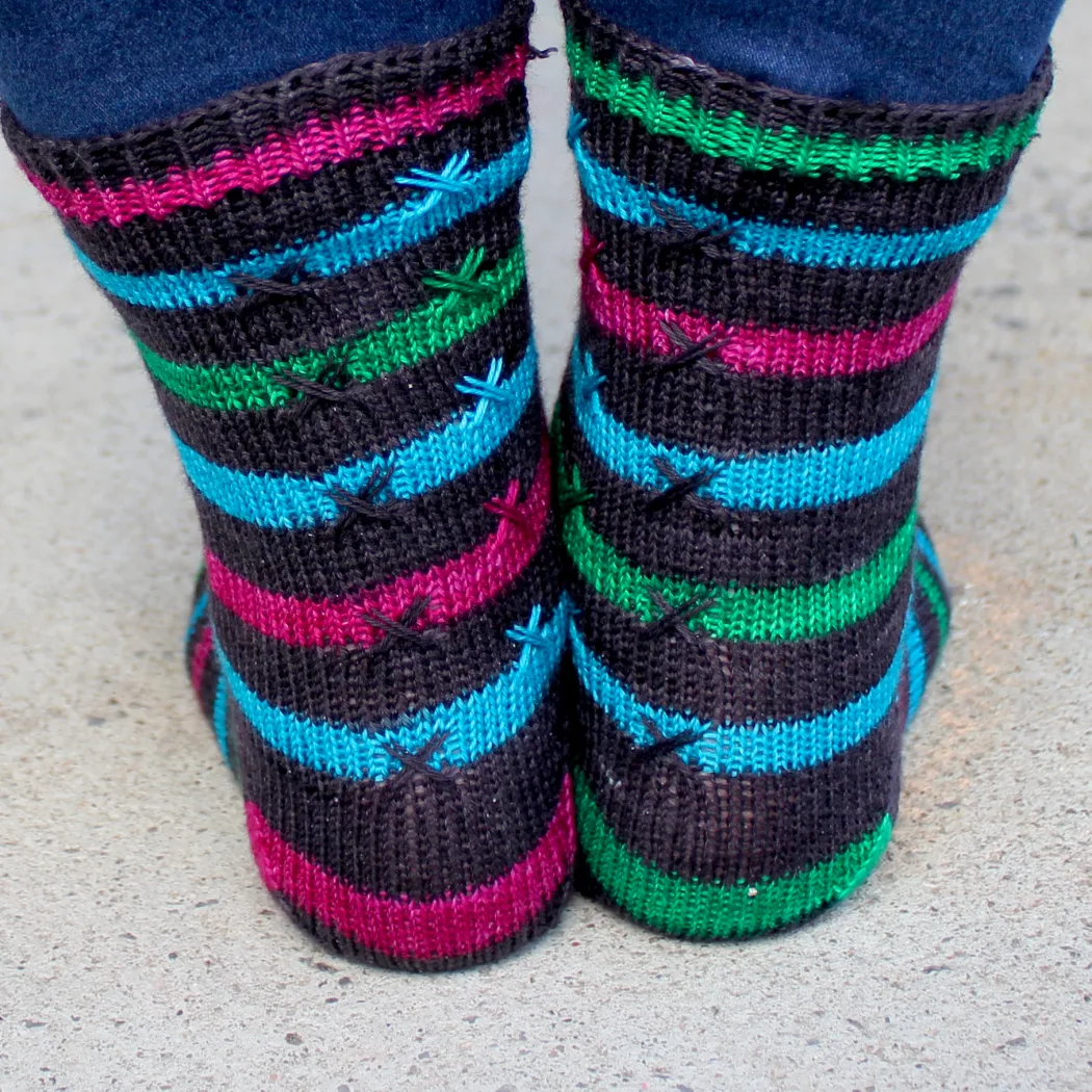 Back view of striped knitted socks with X stitch details on top of the stripes.