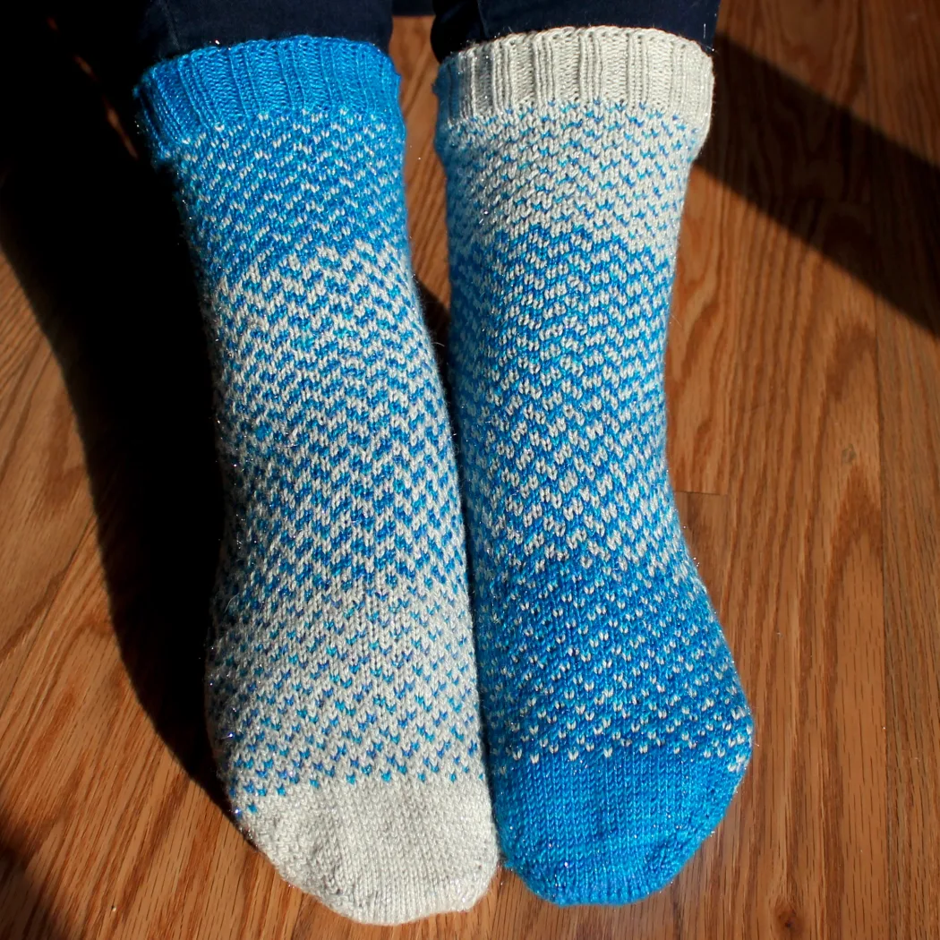 Front view of fraternal blue and white sparkly colourwork socks.