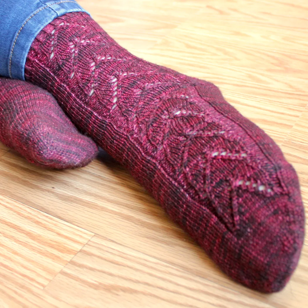 Close up of feet wearing red socks with lace panel of interlocking hearts.