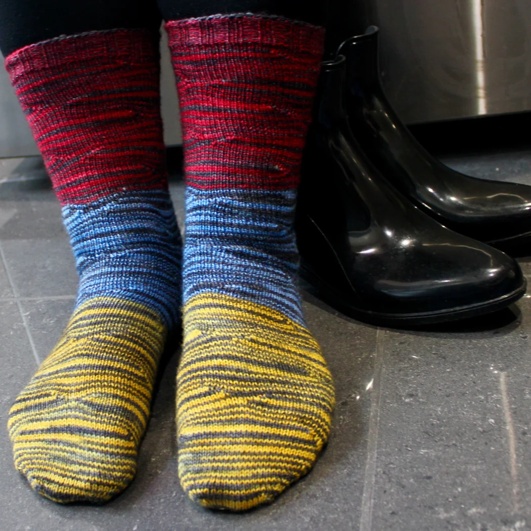 Front view of feet wearing red, yellow, and blue socks with distorted black stripes.