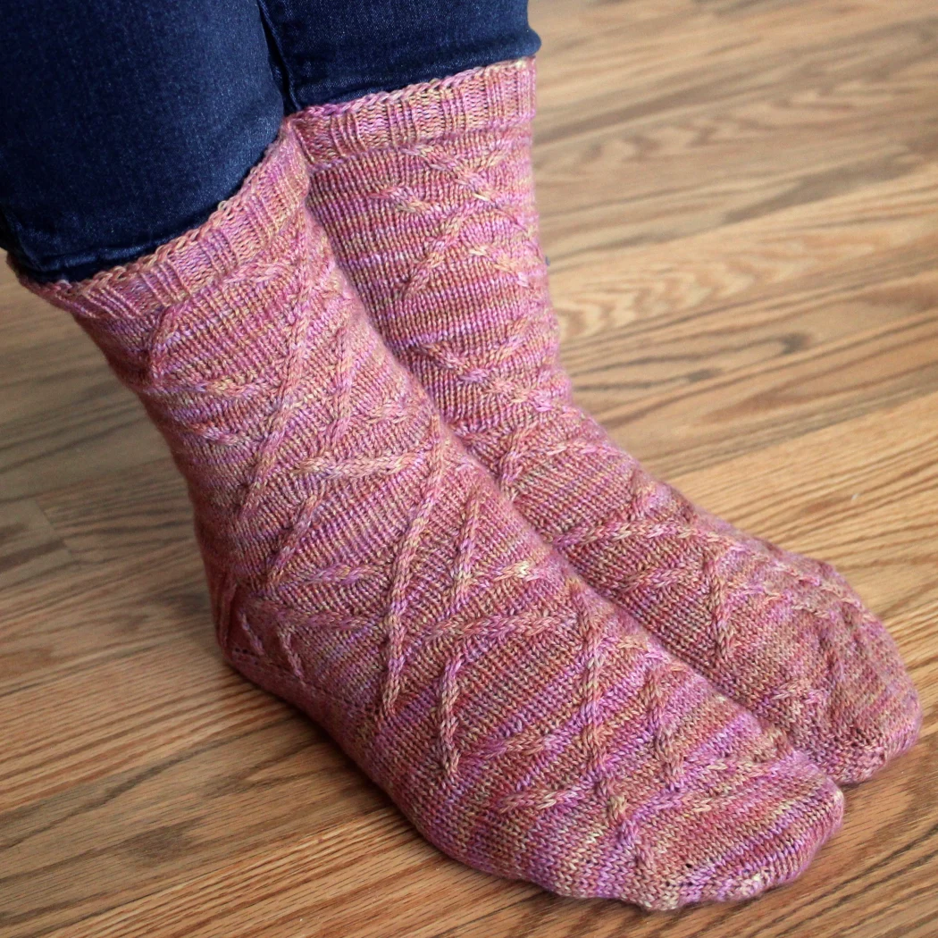 Crossed feet wearing pink-orange socks with cabled surface detail.