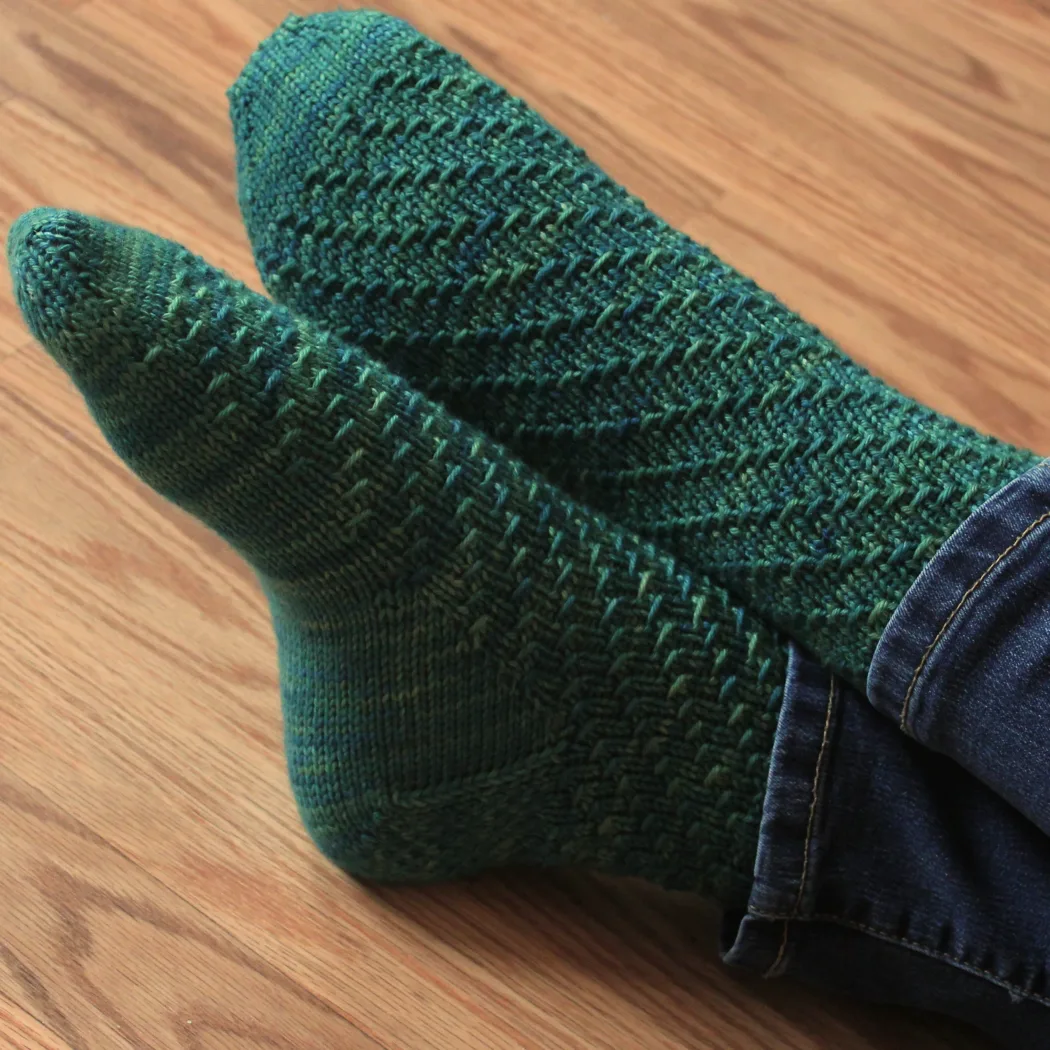 Crossed feet wearing rich green socks with spiral texture.