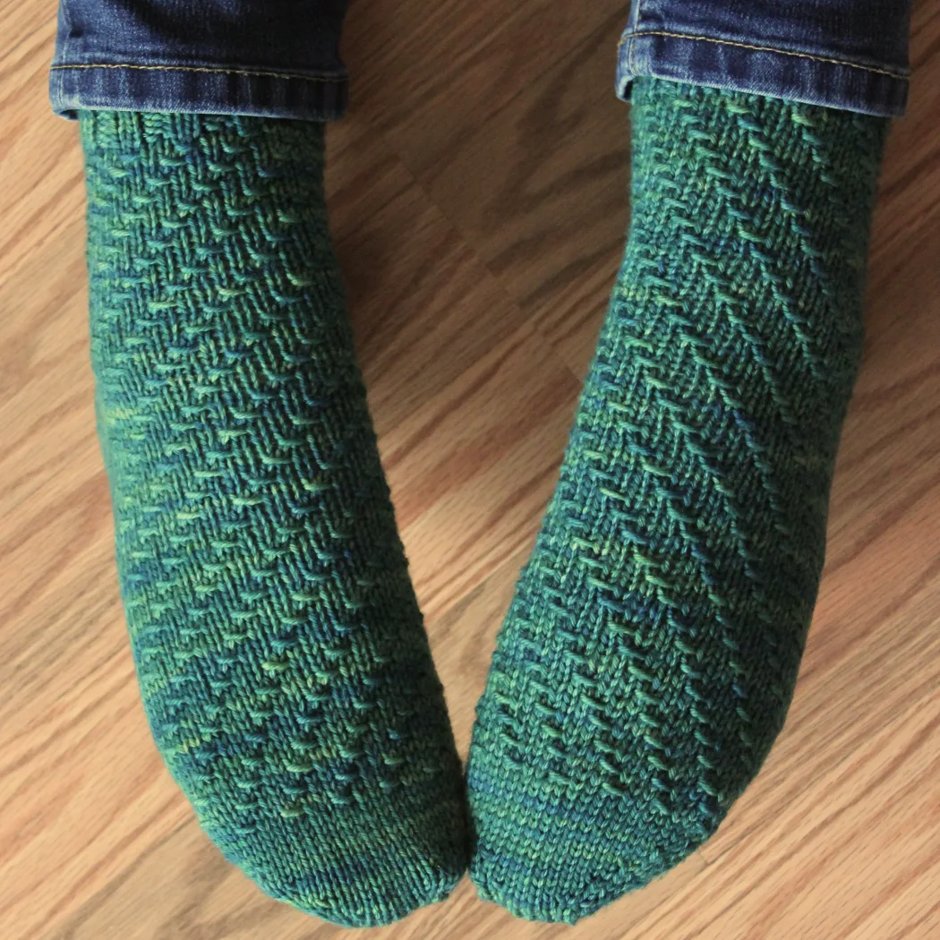 Top-down view of feet wearing rich green socks with mirrored spiral texture.