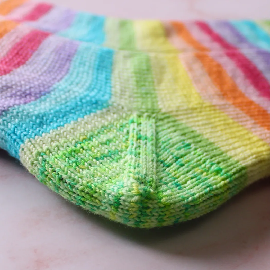 Close up of green speckled heel on rainbow striped socks.