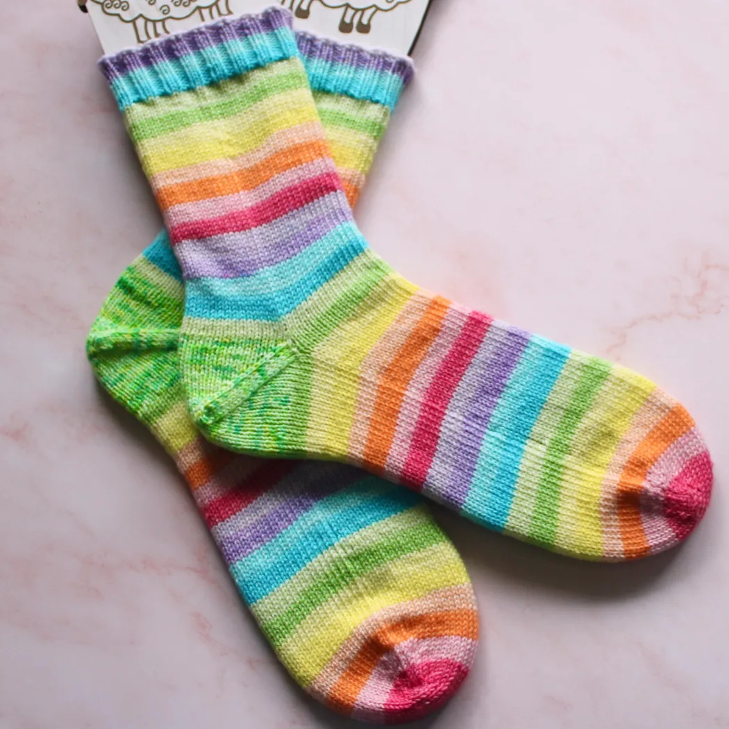 Wide view of rainbow striped socks with green speckled heels on sock blockers.