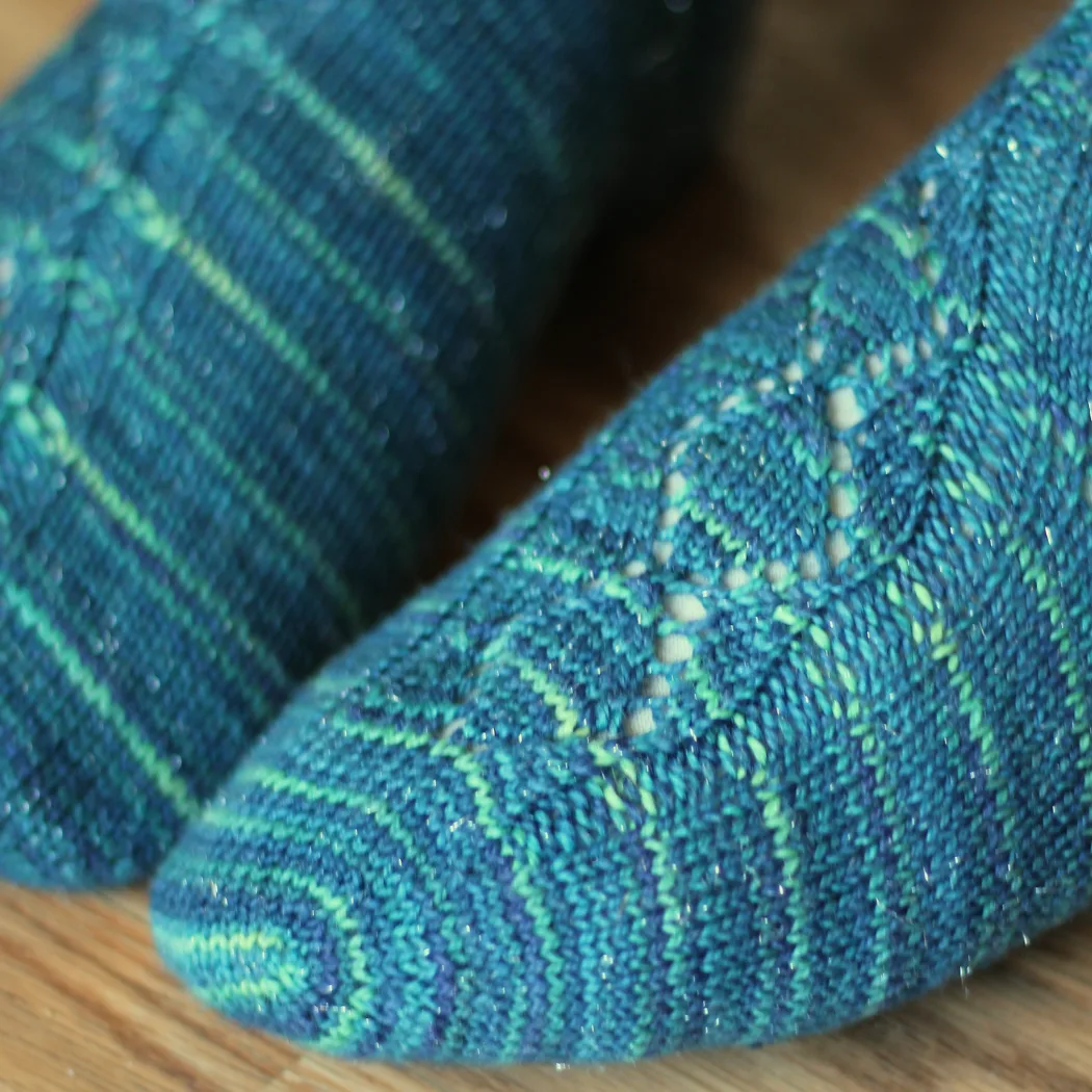 Close up of feet wearing blue socks with diamond-and-curves lace panel.