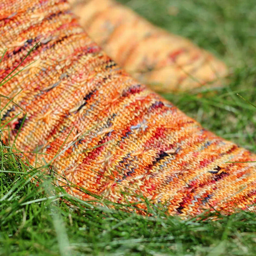 Close up of orange socks with asterix-like cable texture.