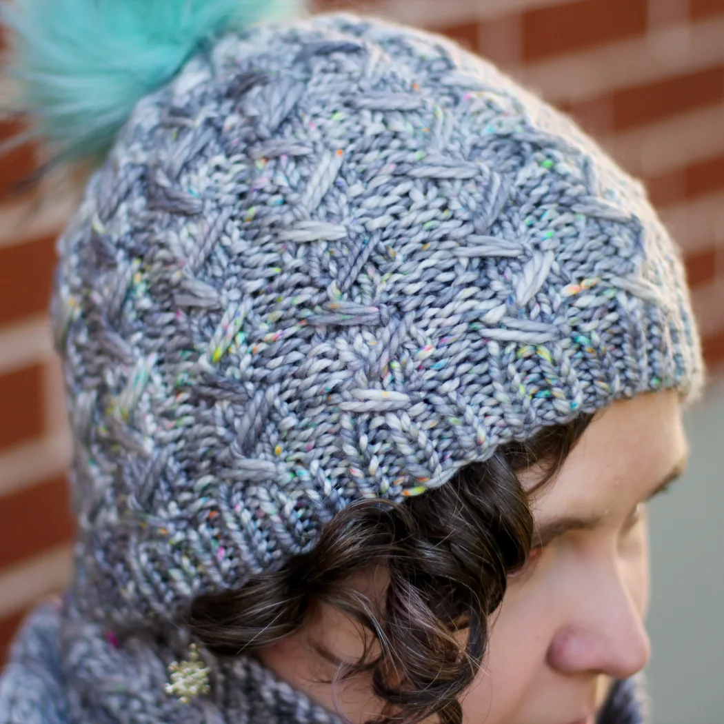 Woman wearing grey knitted toque with textured ribbing and mint green pompom.