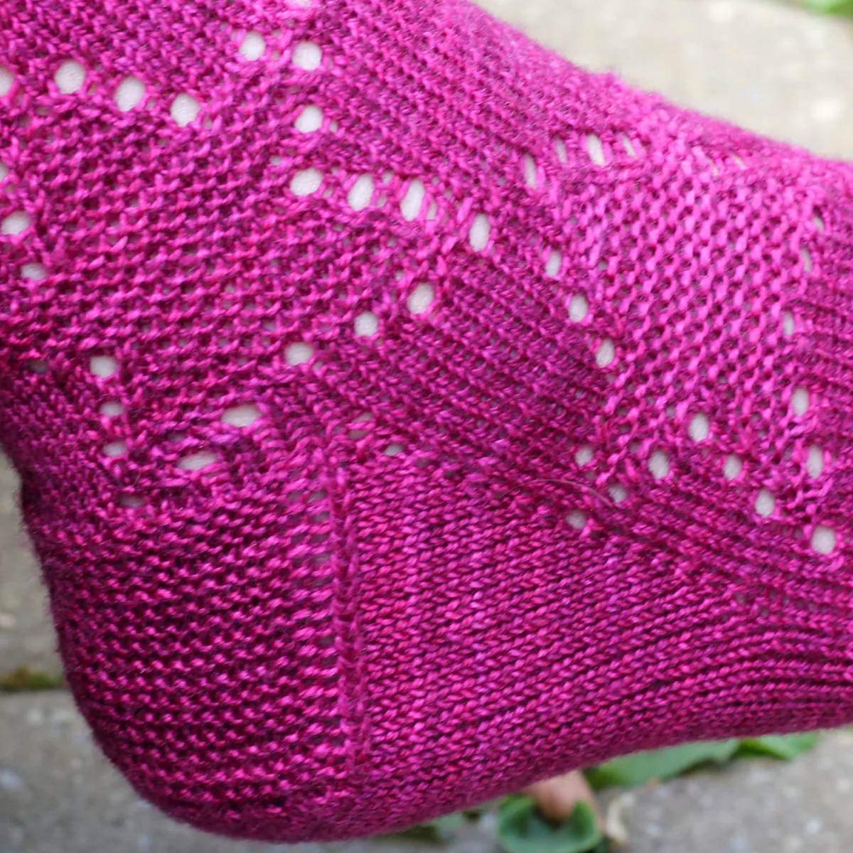 Foot wearing dark pink knitted sock with gusset and heel flap and star motifs.