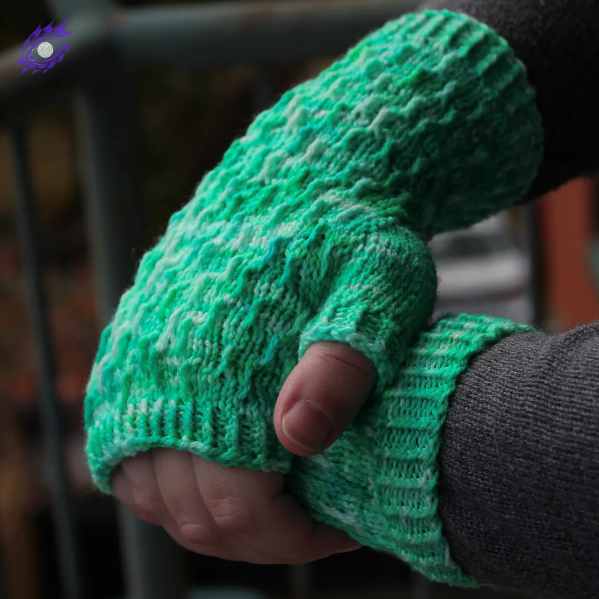 Side view of hands draped over each other wearing bright green fingerless mitts with twisted surface detail.