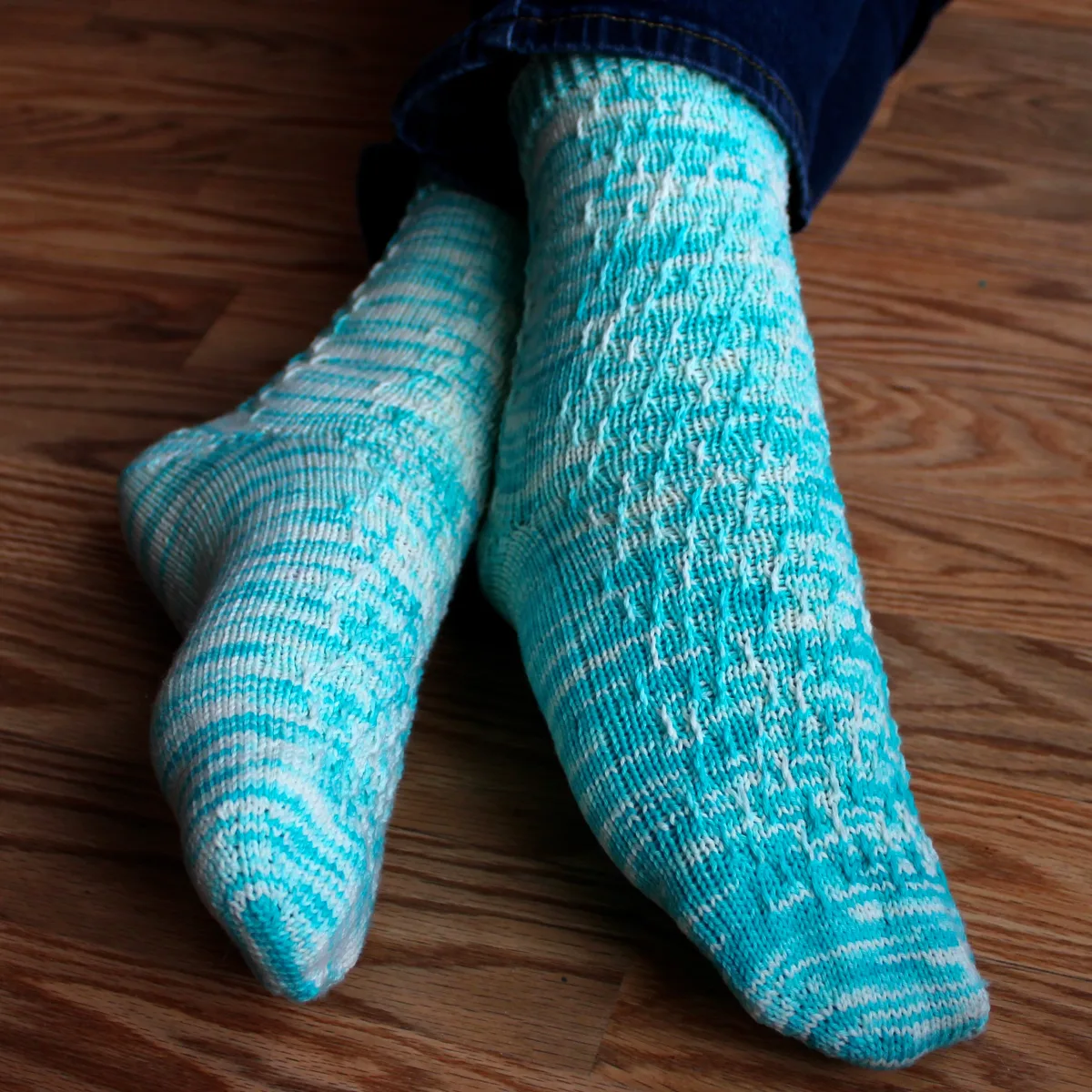 Crossed feet wearing bright blue and white socks with twisted surface detail.