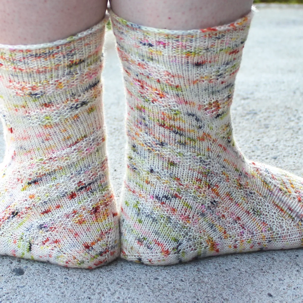 Back view of heavily-speckled white socks with semicircular texture details.