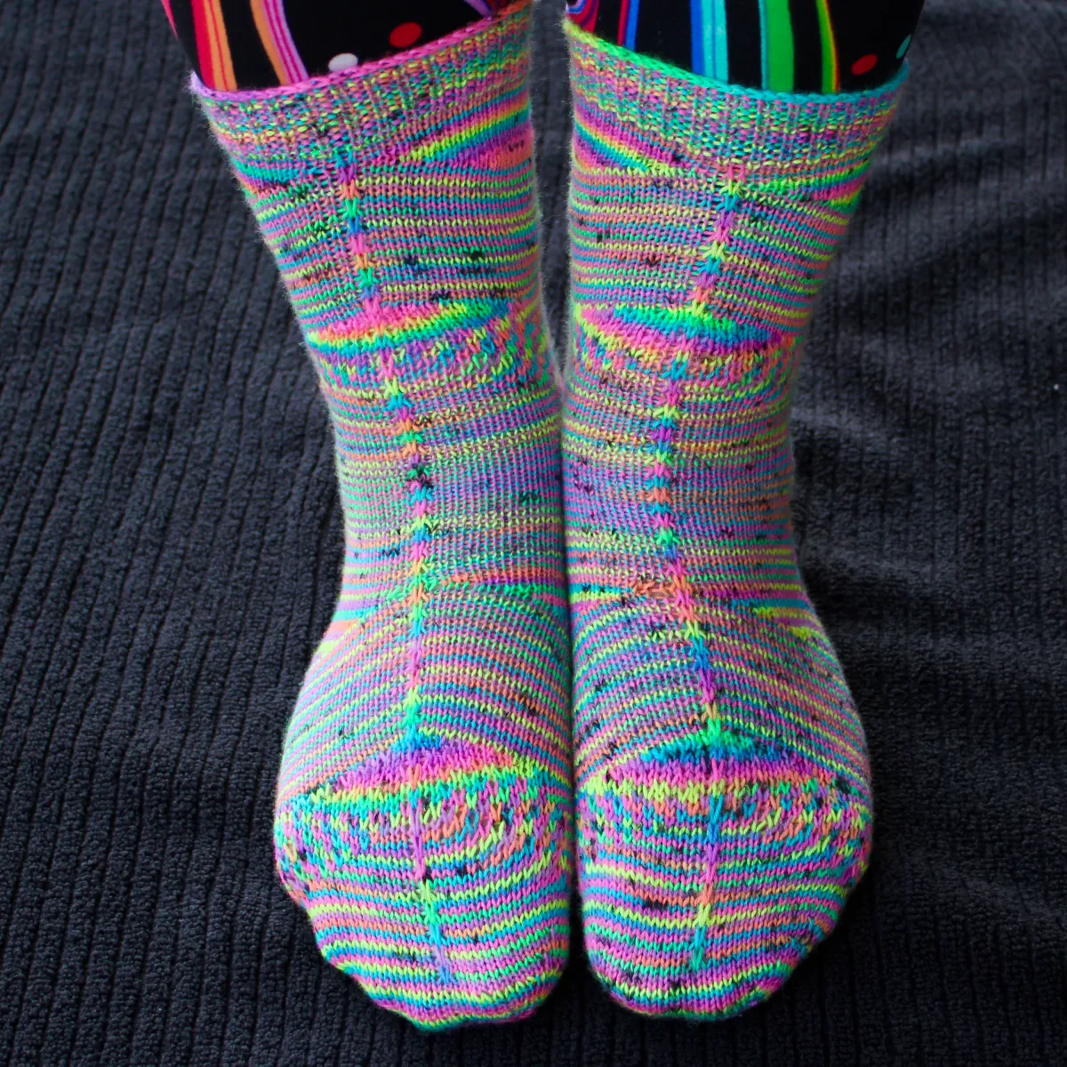 Front view of rainbow socks with shifting and pooling colour patterns and surface texture.