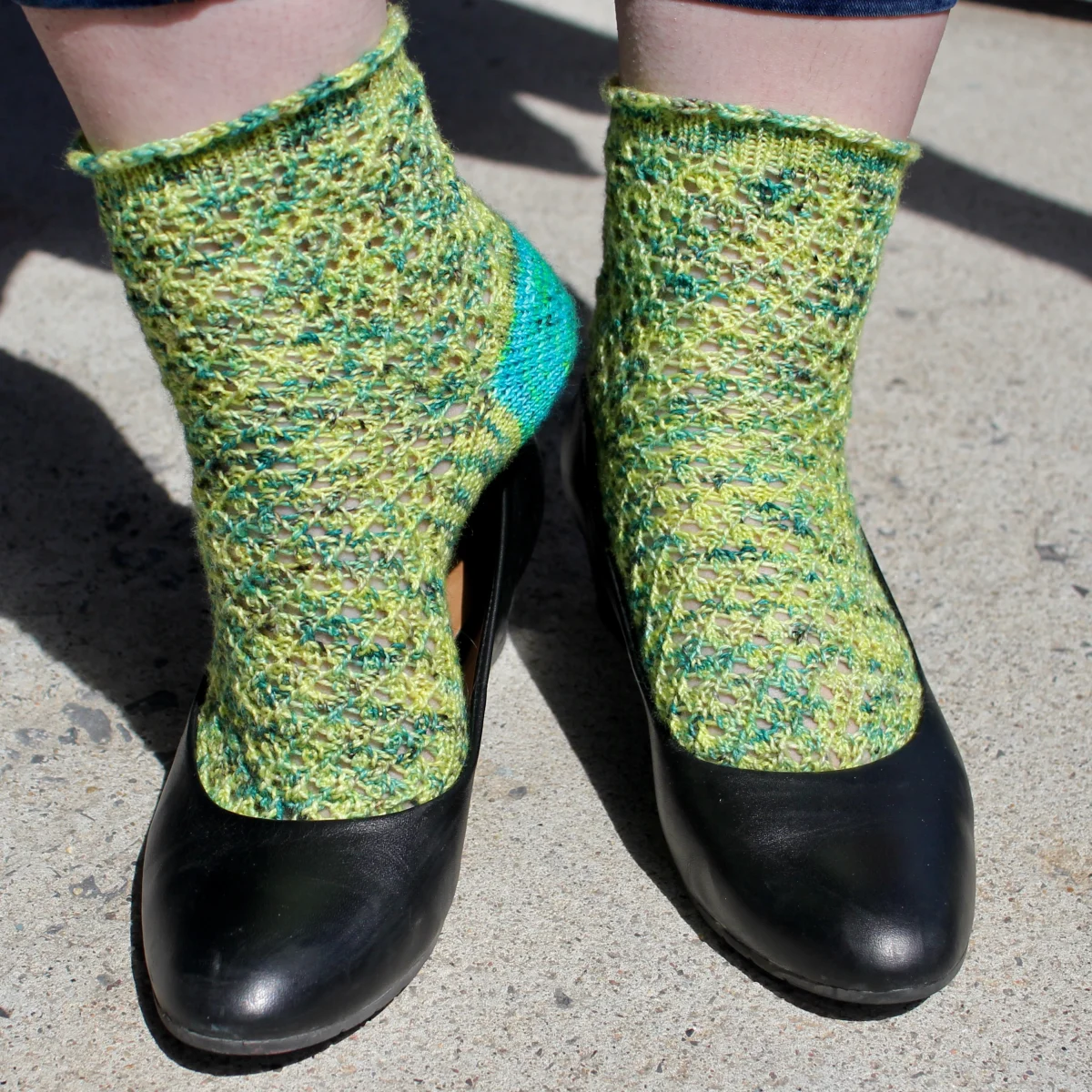 Feet wearing yellow and green lace socks; one foot is turned sideways to reveal a bright blue sock heel.