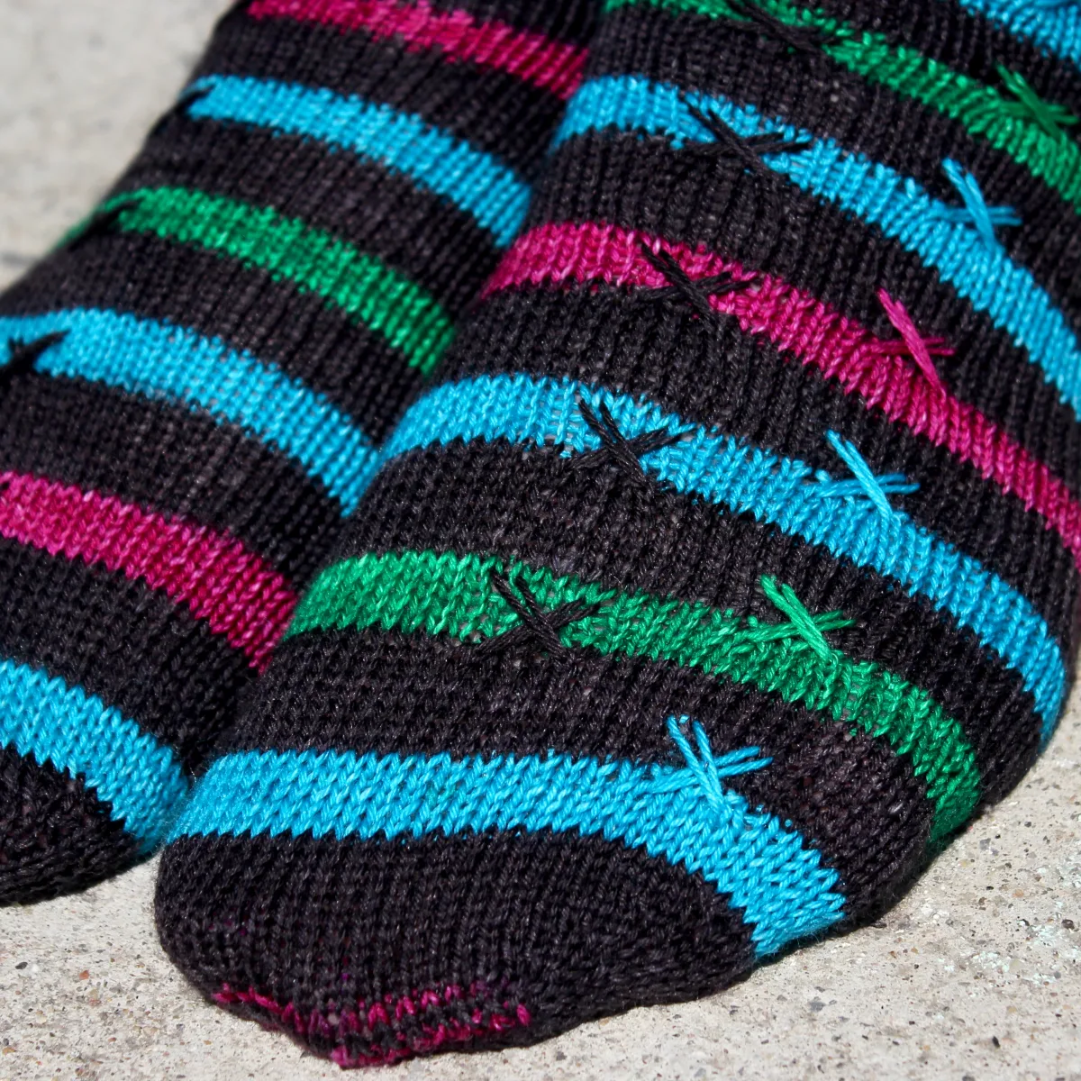 Close up of striped knitted socks with X stitch details on top of the stripes.