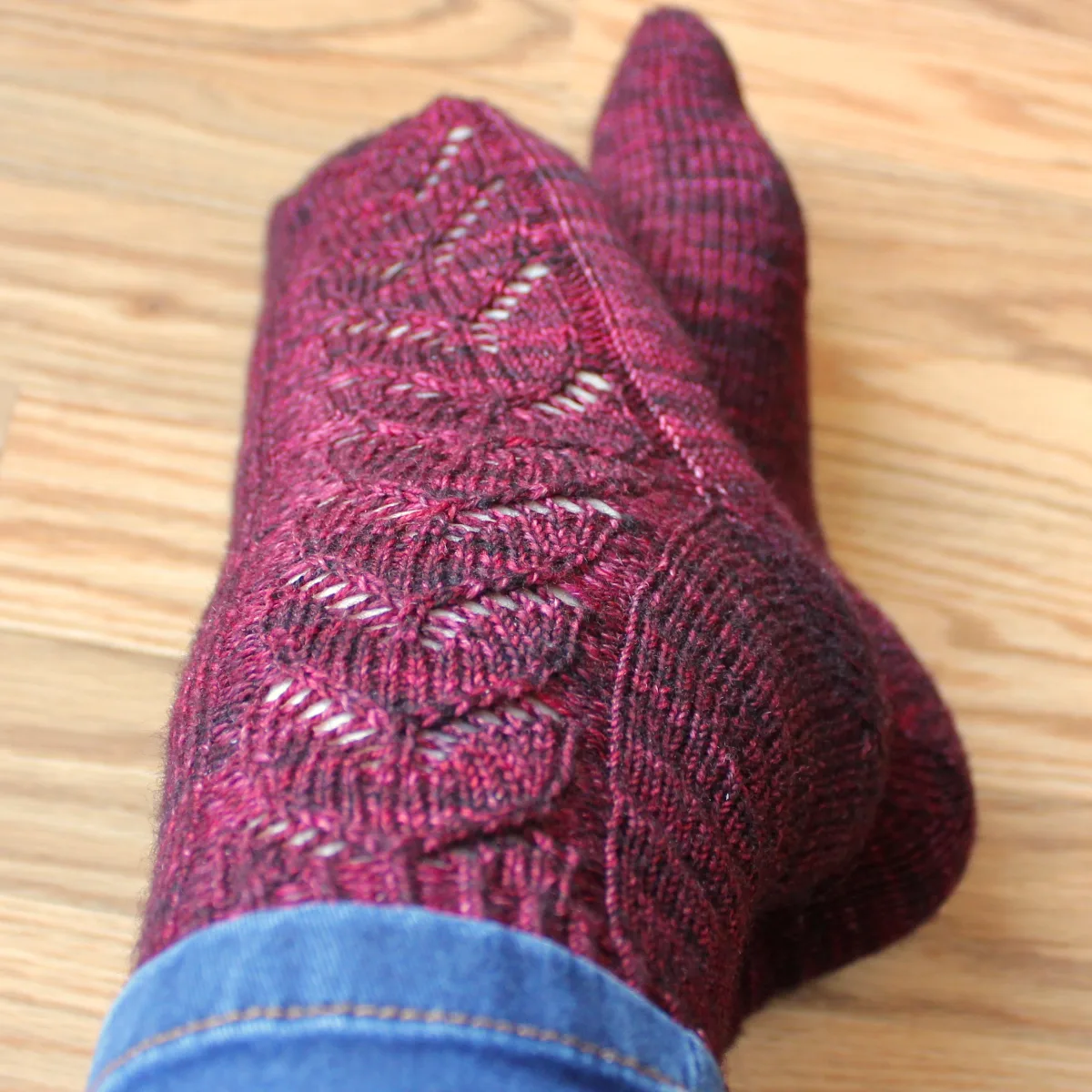 Top-down view of feet wearing red socks with lace panel of interlocking hearts.