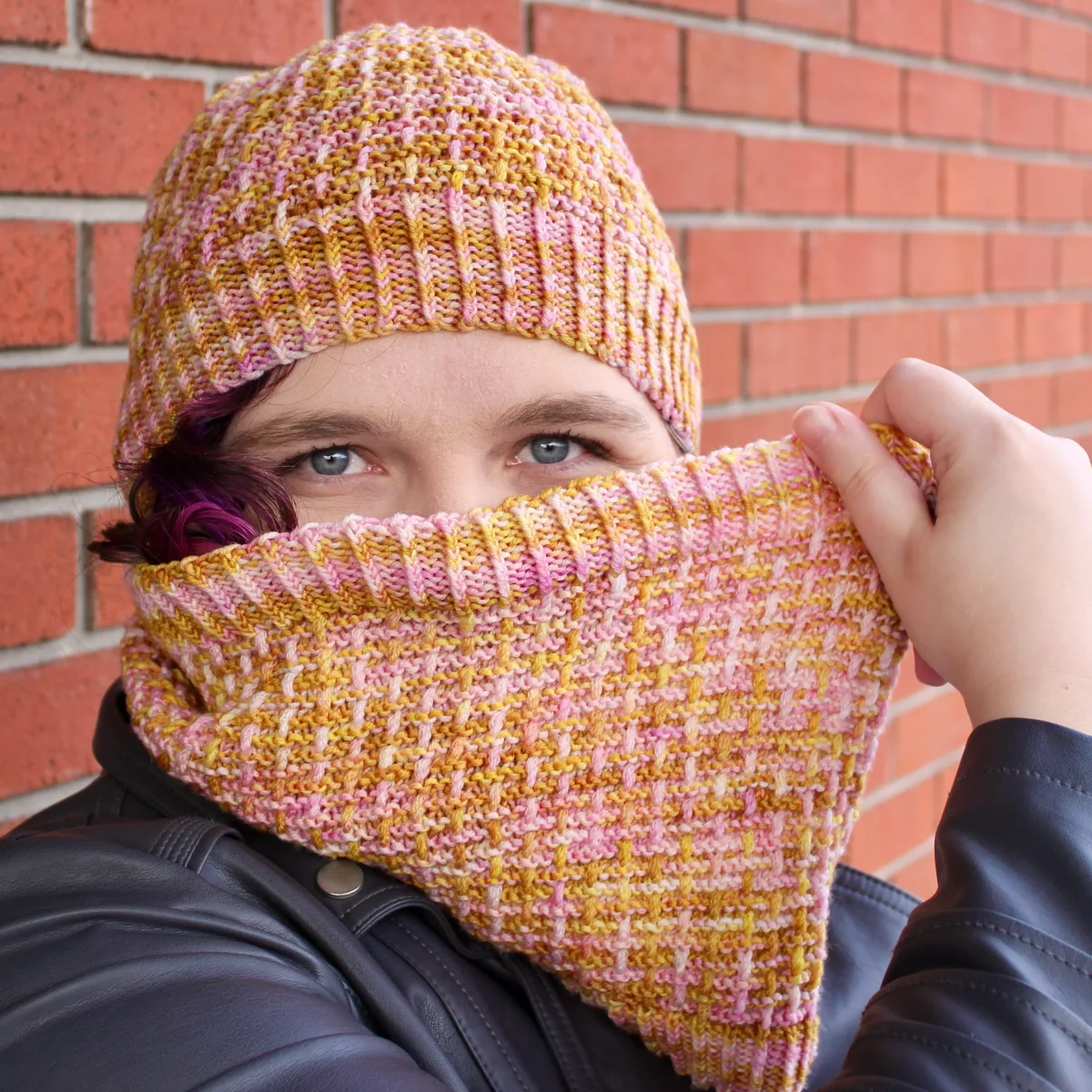 Woman wearing yellow and pink hat and cowl with matching twisted and ridged surface texture.