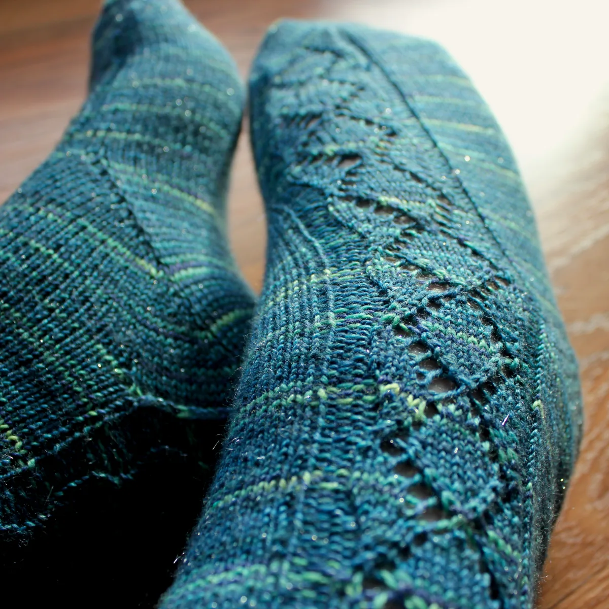 Close up of feet wearing blue socks with lace panel that runs diagonally across the foot.