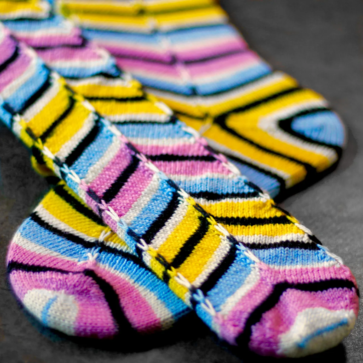 Striped knitted socks crossed over each other on sock blockers with graphic distorted diagonal pattern and matching heel.